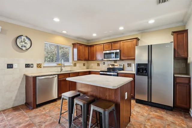 a kitchen with stainless steel appliances granite countertop a stove top oven a sink dishwasher and a refrigerator