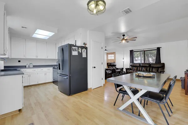 a kitchen with a refrigerator a stove a dining table and chairs with wooden floor