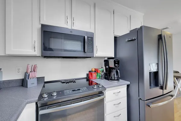 a kitchen with stainless steel appliances granite countertop a refrigerator and a stove top oven
