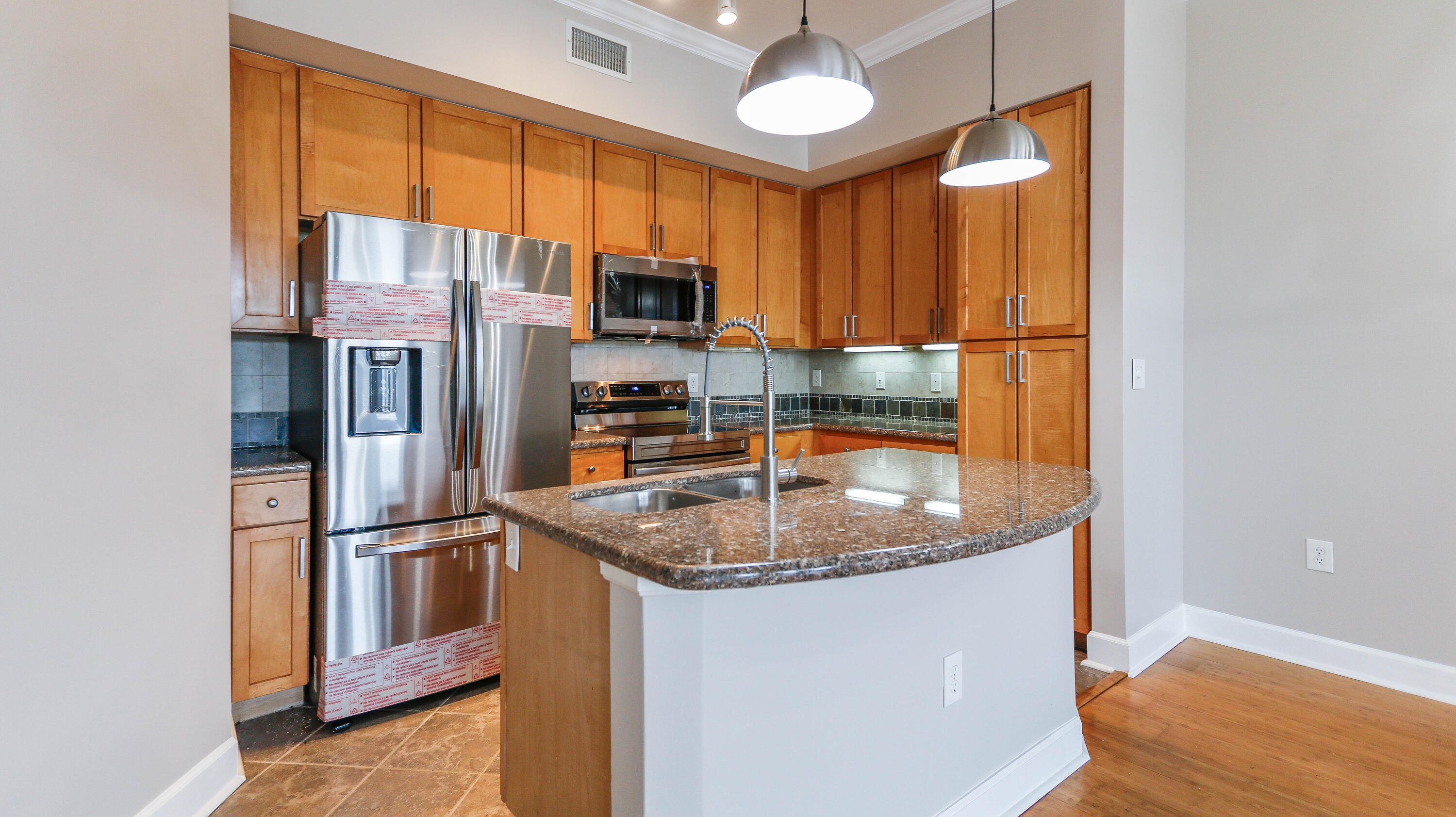 8700 Front Beach Road, Unit 1311 Panama City Beach, FL 32407 - Photo 11 of 65 a kitchen with stainless steel appliances granite countertop a refrigerator a stove and a sink with wooden floor