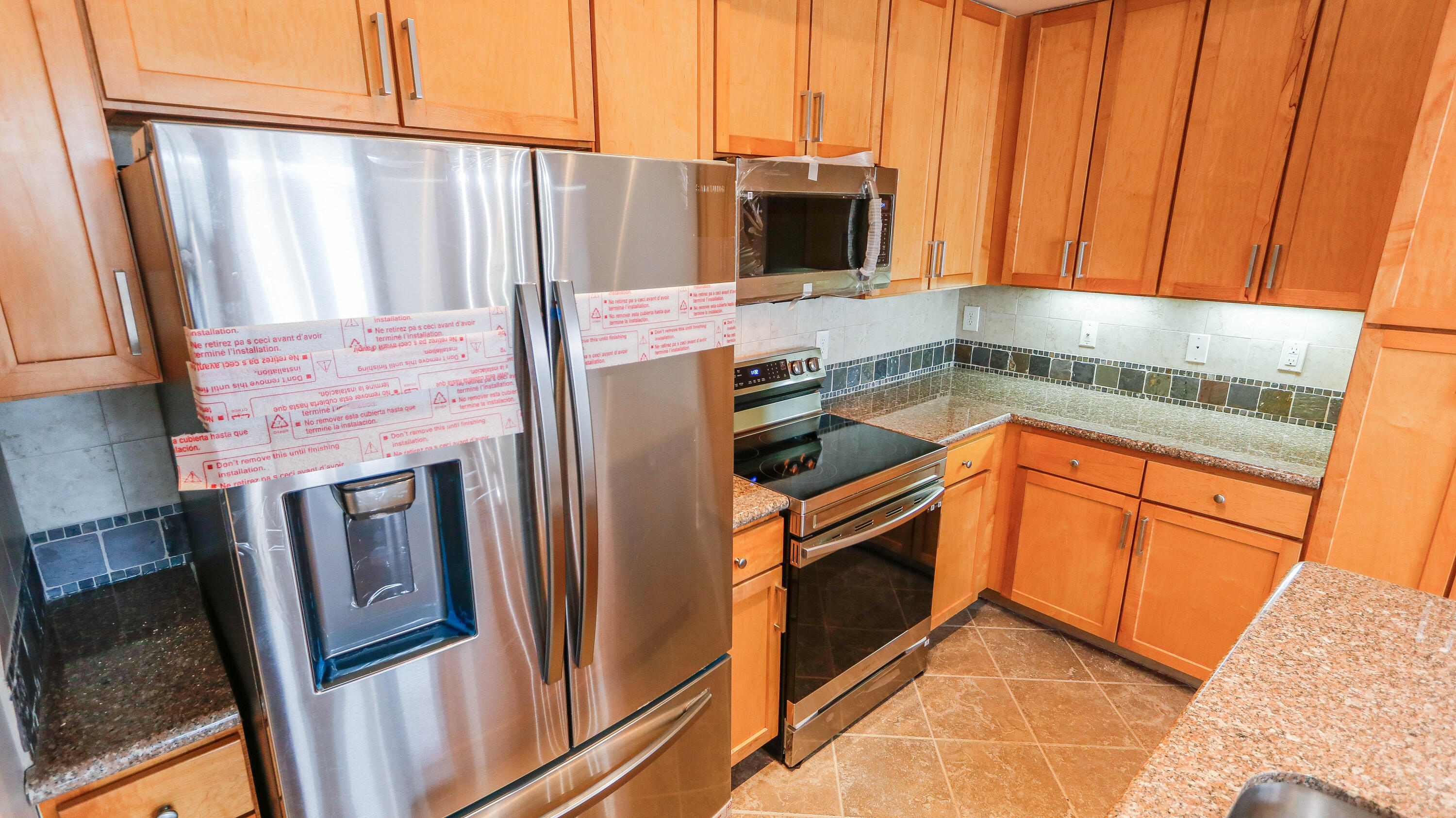 8700 Front Beach Road, Unit 1311 Panama City Beach, FL 32407 - Photo 23 of 65 a kitchen with stainless steel appliances granite countertop a refrigerator a stove and a sink with wooden cabinets