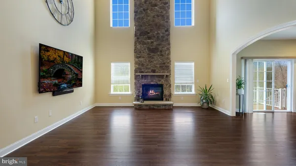 a view of an empty room with wooden floor fireplace and a window