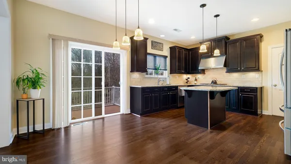 a kitchen with stainless steel appliances granite countertop a stove a sink a refrigerator and a wooden cabinets