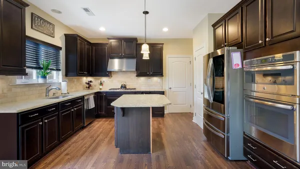 a kitchen with stainless steel appliances kitchen island granite countertop a stove refrigerator and sink