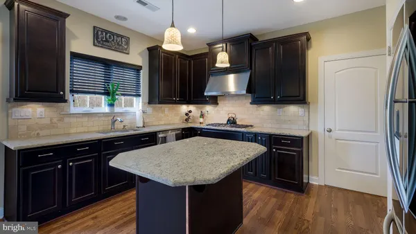 a kitchen with a sink a kitchen island wooden cabinetry and stainless steel appliances