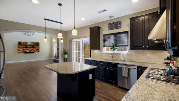 a kitchen with stainless steel appliances granite countertop a sink a stove and a wooden floors