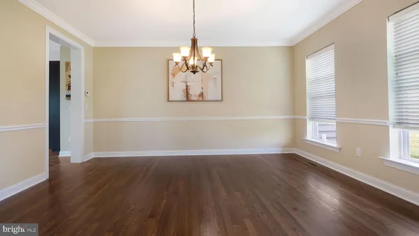 an empty room with wooden floor chandelier and windows
