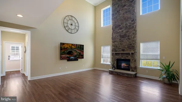 an empty room with wooden floor a fireplace and a potted plant