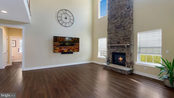 an empty room with wooden floor a fireplace and a chandelier