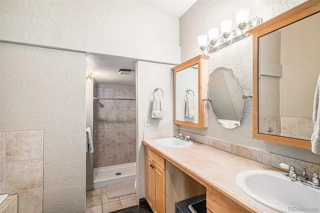 a bathroom with a double vanity sink mirror and shower