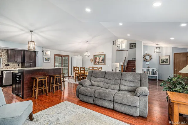 a living room with furniture kitchen view and a wooden floor