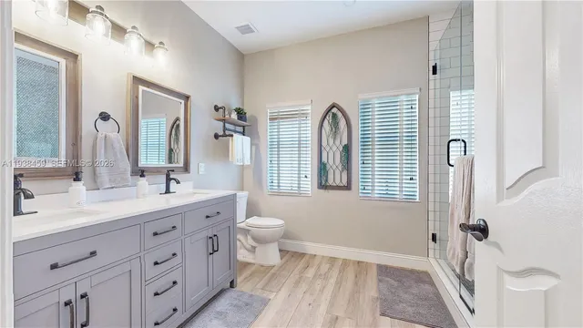 a bathroom with a double vanity sink a mirror a toilet and a window