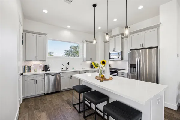 a kitchen with a sink a refrigerator and chairs