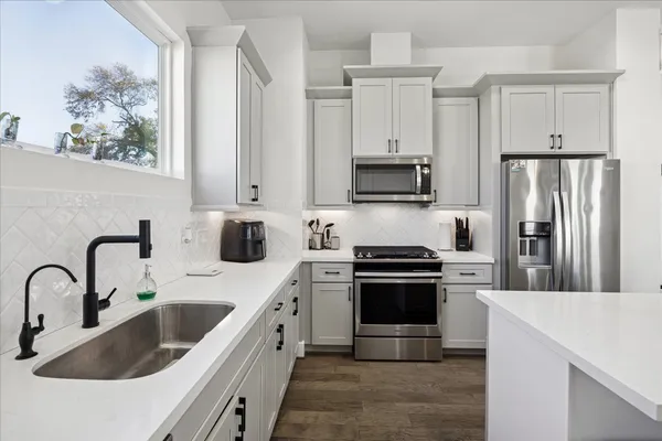a kitchen with stainless steel appliances granite countertop a sink a stove a refrigerator and cabinets