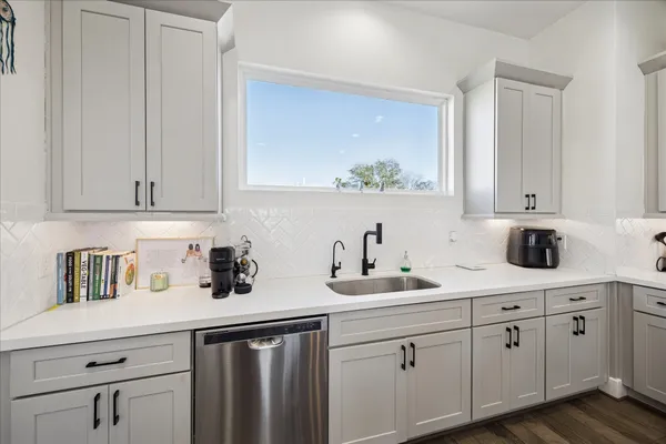 a kitchen with white cabinets and sink