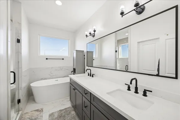 a bathroom with a double vanity sink mirror and bathtub