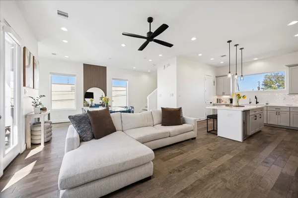 a living room with furniture kitchen view and a chandelier