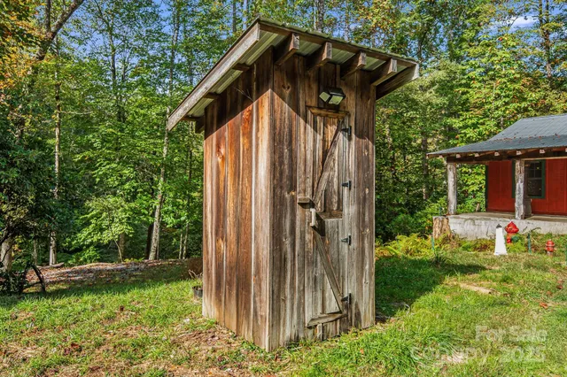 a view of a wooden house with a small yard and a large tree