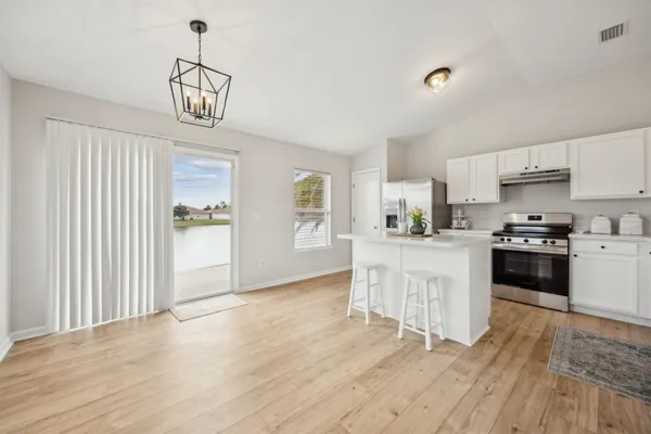 a kitchen with granite countertop a refrigerator stove top oven and cabinets