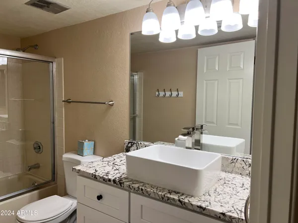 a bathroom with a sink a toilet and shower