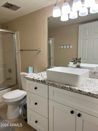 a bathroom with a granite countertop toilet sink and mirror
