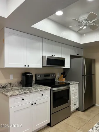 a kitchen with granite countertop a stove sink and refrigerator
