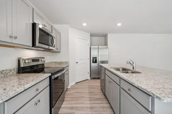 a kitchen with stainless steel appliances granite countertop a sink stove microwave and refrigerator