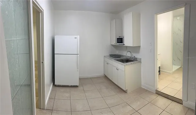 a kitchen with a refrigerator and white cabinets