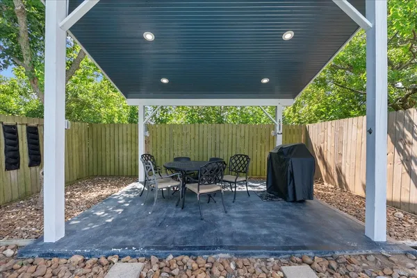 a view of a patio with table and chairs potted plants and large tree