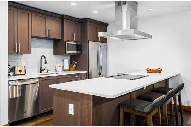 a kitchen with stainless steel appliances a table chairs refrigerator and sink