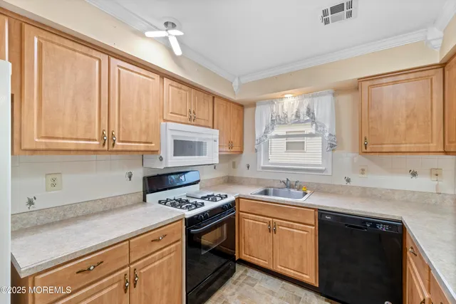 a kitchen with stainless steel appliances granite countertop a sink a stove cabinets and a window