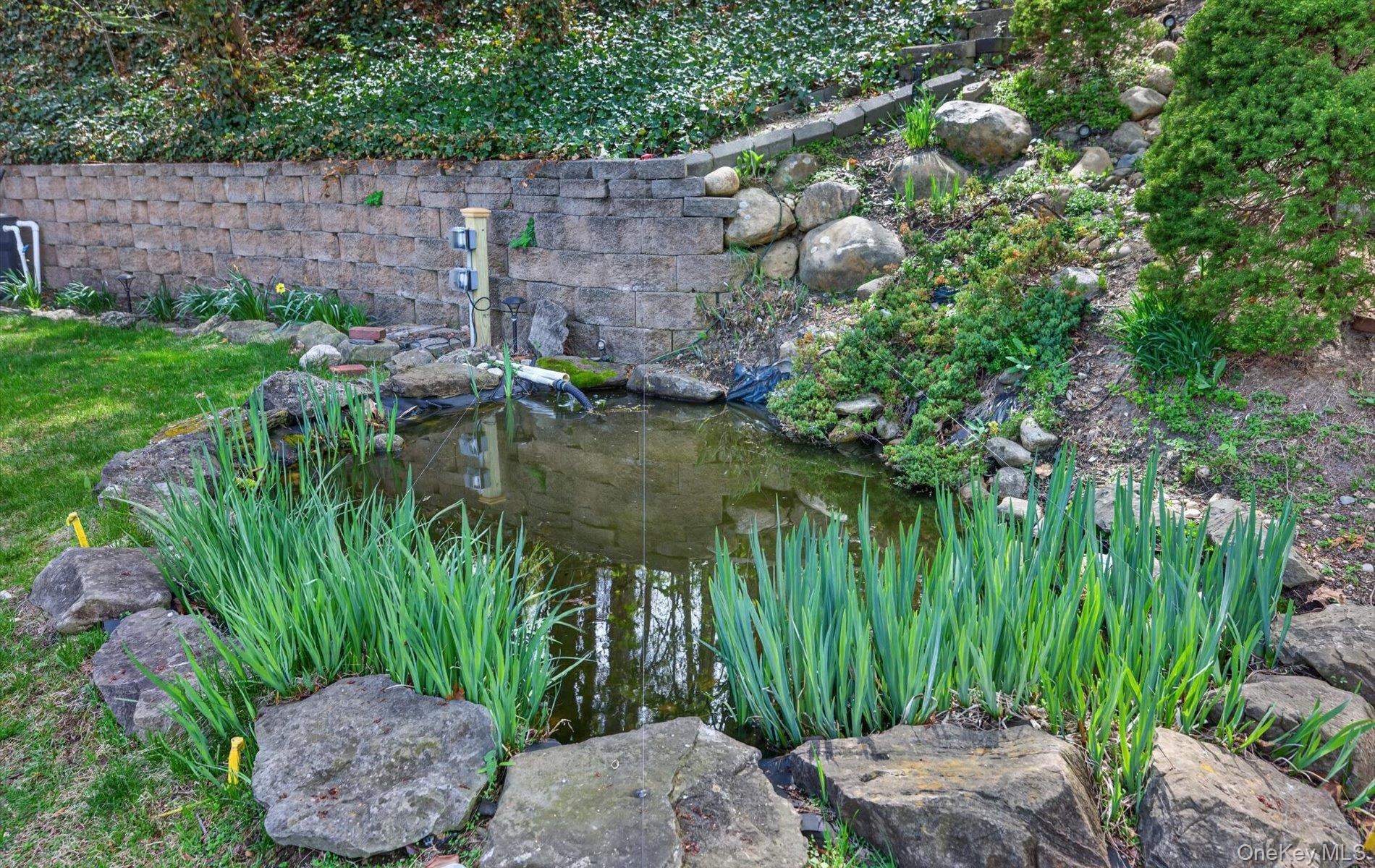 16 East Slope Road Bayville, NY 11709 - Photo 38 of 48 Backyard water feature surrounded by natural stone and lush plantings