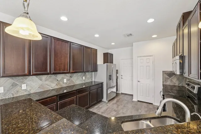 a kitchen with stainless steel appliances granite countertop a sink refrigerator and cabinets