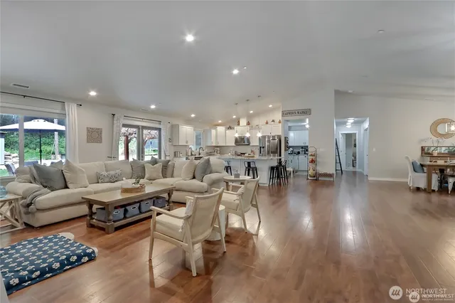 a living room with lots of furniture hard wood floor and a table