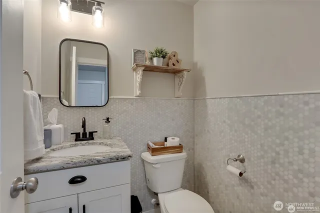 a bathroom with a granite countertop toilet sink and mirror