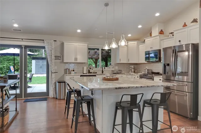 a kitchen with stainless steel appliances granite countertop a table chairs a sink and a refrigerator