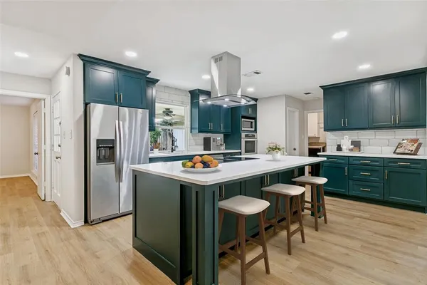 a kitchen with stainless steel appliances a table and chairs in it