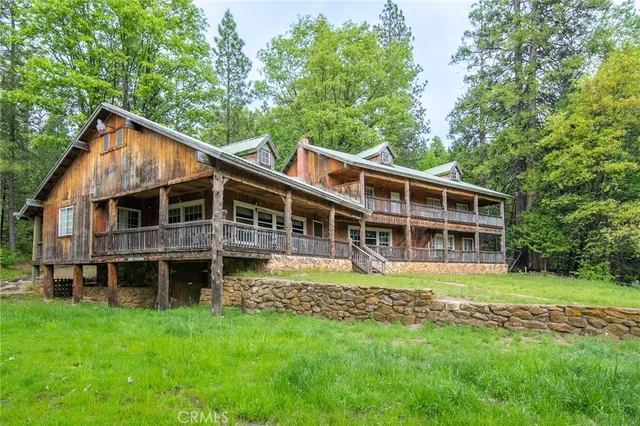 a view of a house with a big yard and large trees