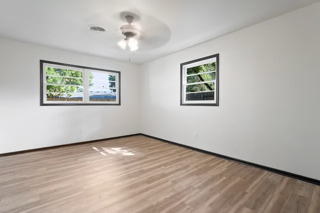 a view of an empty room with wooden floor and a window