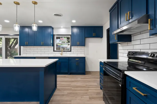 a kitchen with stainless steel appliances granite countertop a sink a stove and a refrigerator