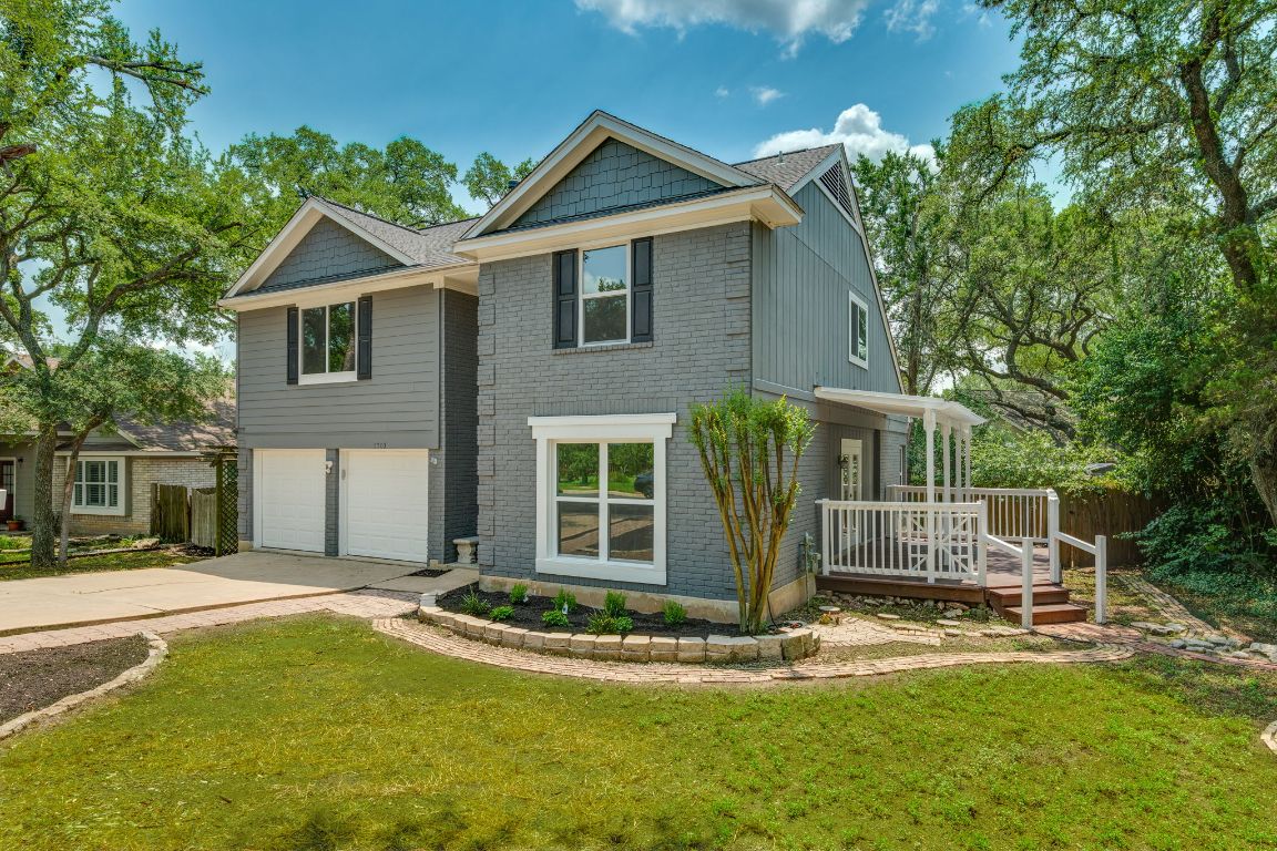 View of front of house featuring concrete driveway, brick siding, a garage, and a deck