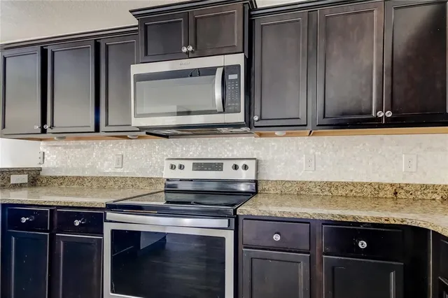 a kitchen with granite countertop a sink stove and microwave