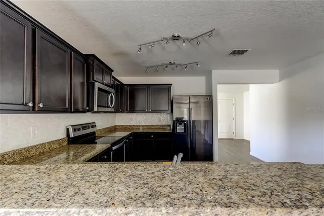 a kitchen with stainless steel appliances granite countertop a refrigerator a stove and a sink