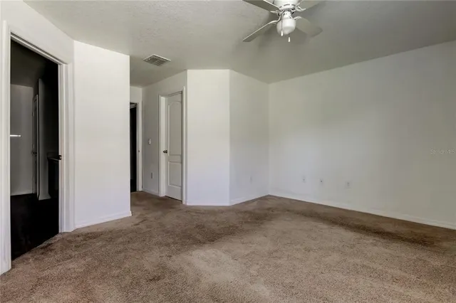 an empty room with closet and ceiling fan