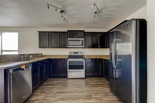 a kitchen with granite countertop a refrigerator and a stove top oven