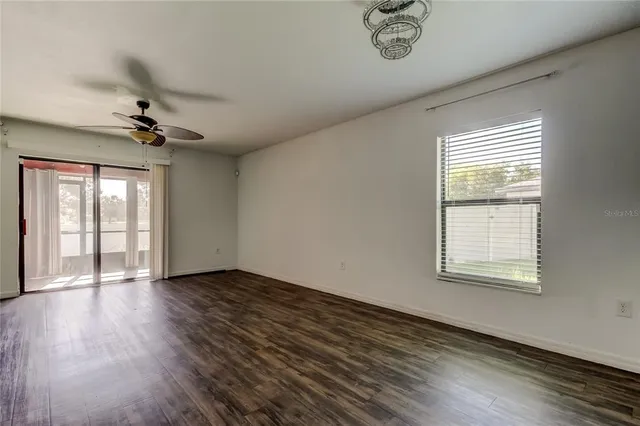 a view of an empty room with a window and wooden floor