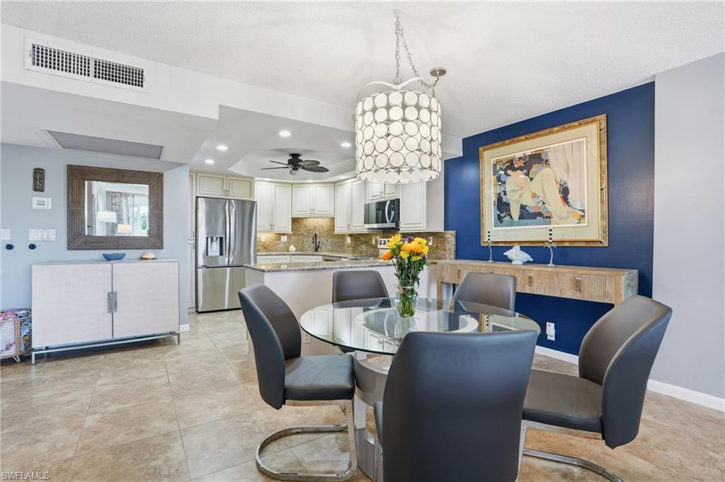 5 Bluebill Avenue, Unit 301 Naples, FL 34108 - Photo 11 of 48 a dining room with furniture a chandelier and wooden floor