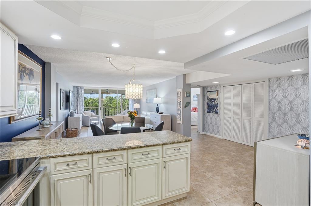 5 Bluebill Avenue, Unit 301 Naples, FL 34108 - Photo 17 of 48 a kitchen with granite countertop a sink stainless steel appliances white cabinets and wooden floor