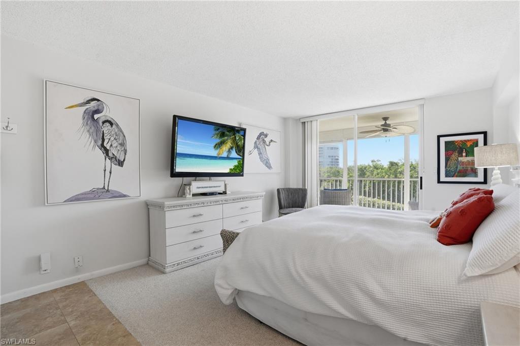 5 Bluebill Avenue, Unit 301 Naples, FL 34108 - Photo 20 of 48 a bedroom with a bed and a flat screen tv