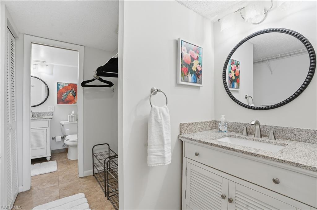5 Bluebill Avenue, Unit 301 Naples, FL 34108 - Photo 21 of 48 a bathroom with a granite countertop double vanity sink mirror and toilet